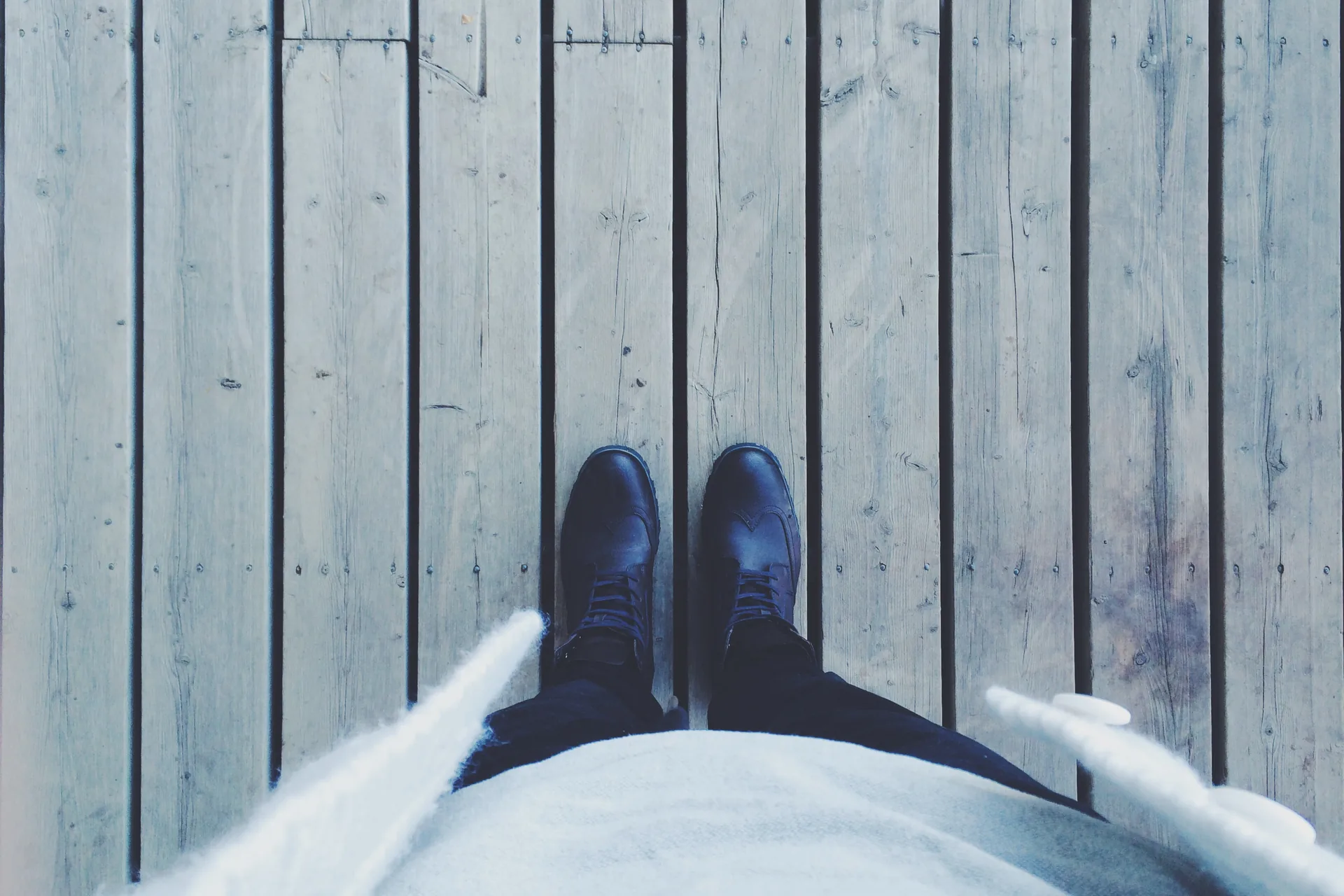 Work boots standing on gray weathered deck boards, seen from above