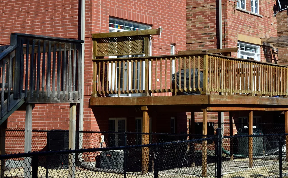Elevated wood deck with pergola behind a row of brick two-story houses