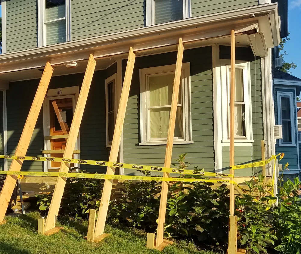 Temporary shoring braces holding a porch roof during a rebuild