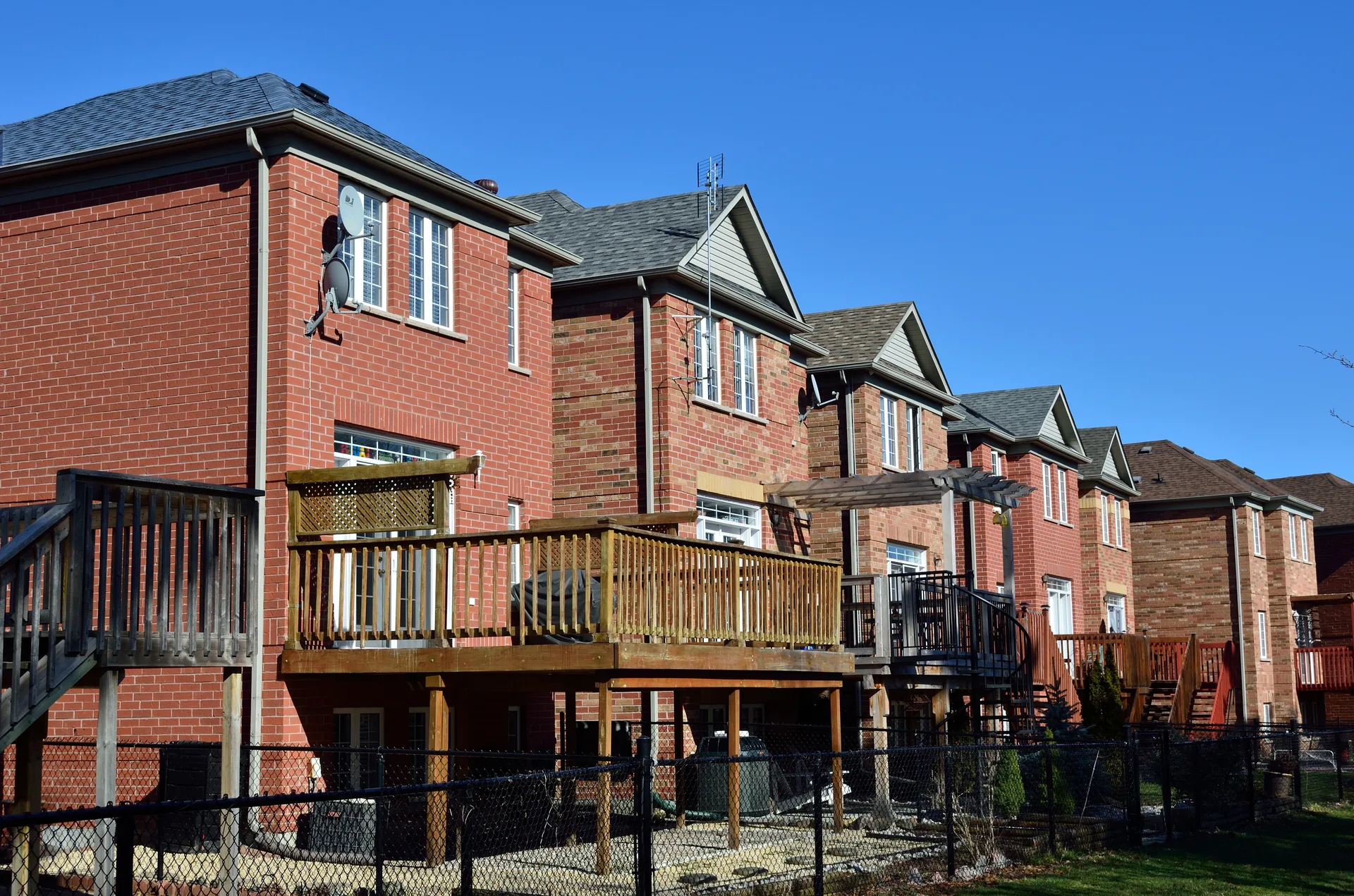 Row of brick two-story houses with elevated wood decks and a pergola