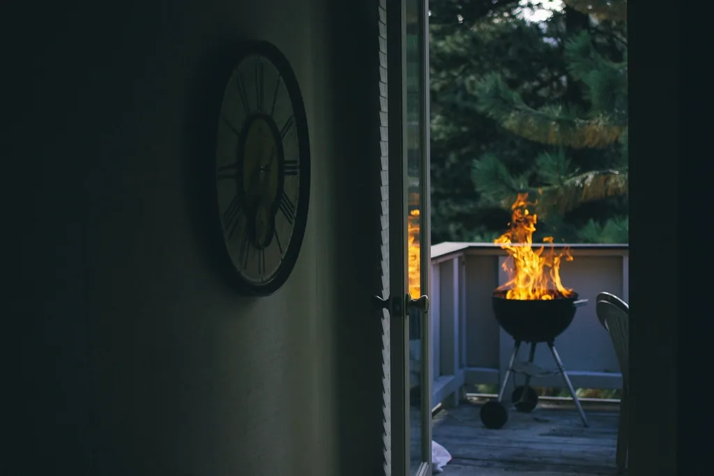 Kettle grill flaming on a deck seen through an open doorway