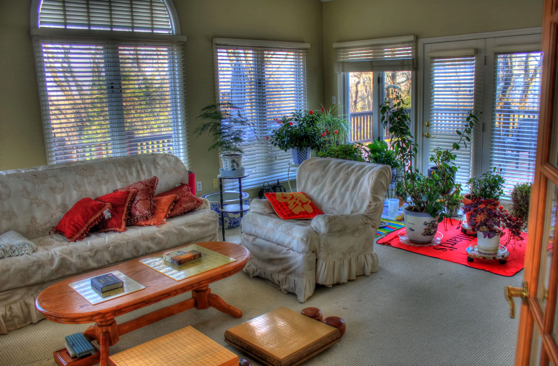 Sunroom with blinds, plants and doors opening toward a deck