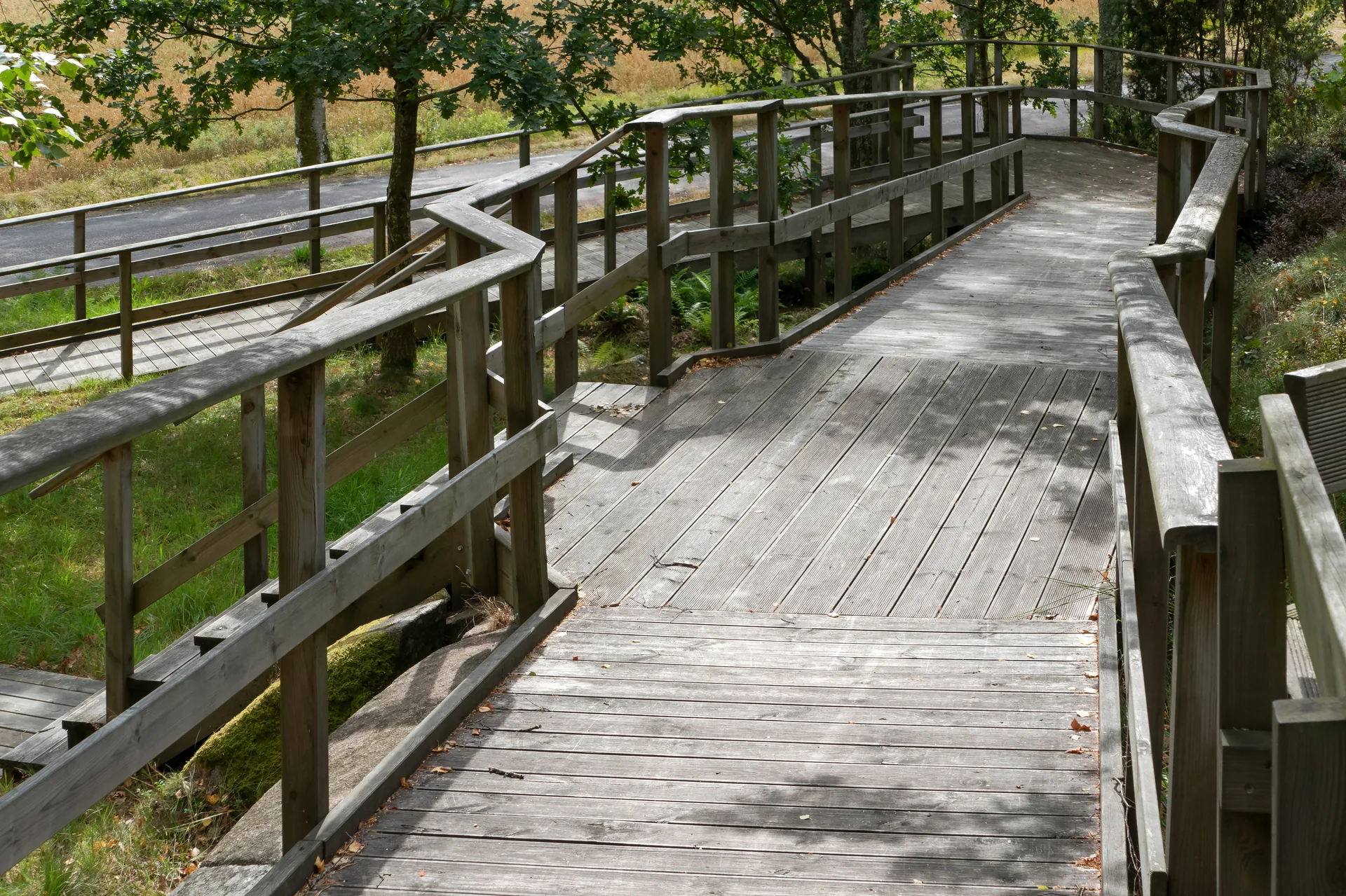 Winding timber walkway with double wood railings among trees