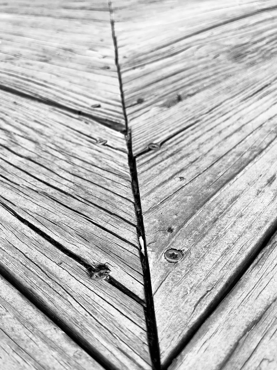 Weathered deck boards with deep cracks and popped fasteners